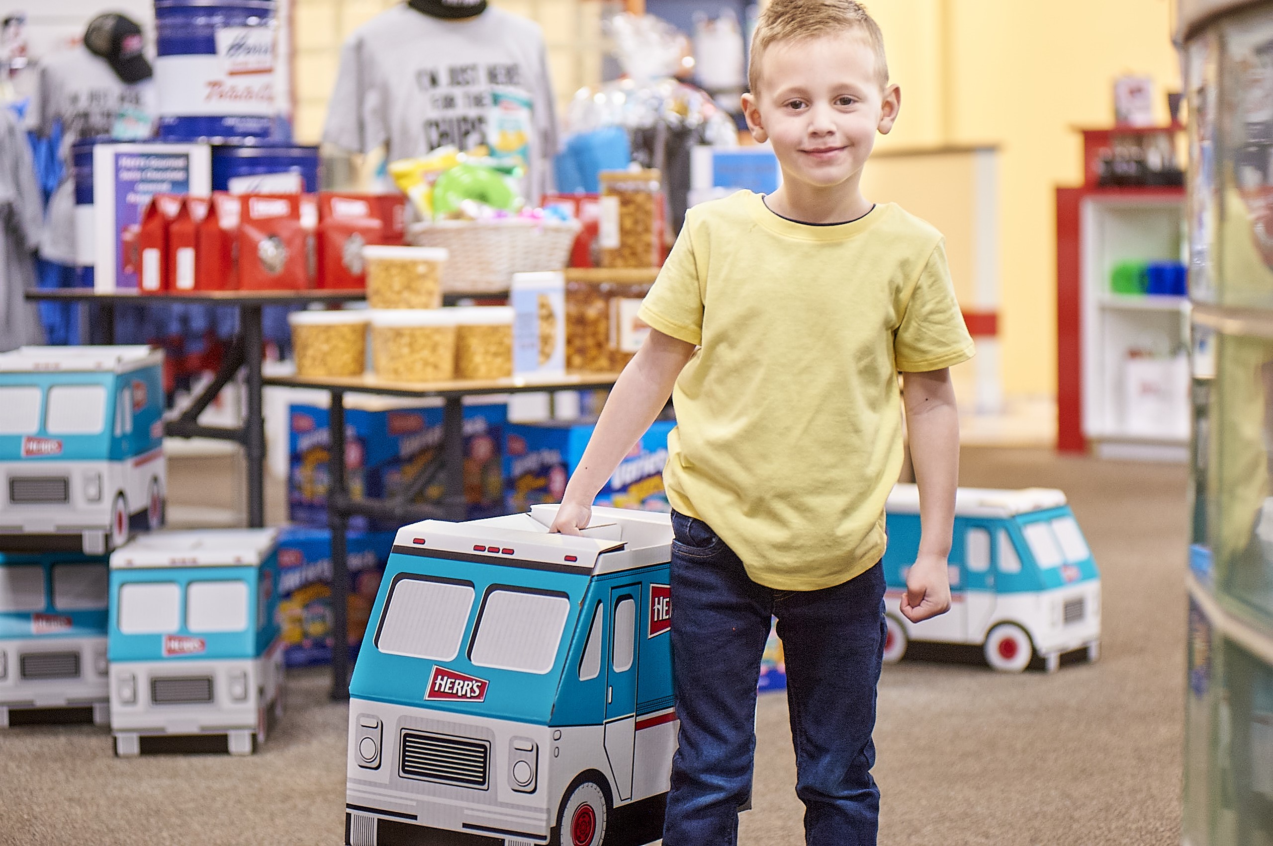 A Kid Holding A Herr's Snack Truck Box In The Herr's Gift Shop